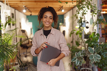 Smiling woman floristic studio owner standing with laptop during working day