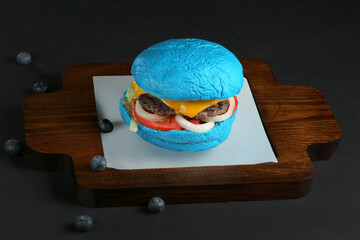 delicious blue color beef burger served on wooden tray black background 