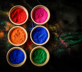 top view of colorful traditional holi powder in bowls isolated on dark background.Space for text . happy holi.Concept Indian color festival called Holi