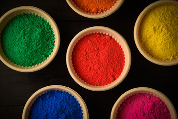 top view of colorful traditional holi powder in bowls isolated on dark background.Space for text . happy holi.Concept Indian color festival called Holi