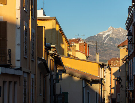 Chiaroscuro Photography Of Houses In Gap, Hautes Alpes, France. Beautiful Orange Evening Light And Mountains Covered With Snow In The Background.