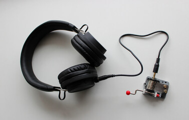 Hand Crank Music Box Connected By Wire With Headphones On Clear White Surface Top View 