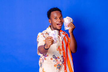 happy and excited young african man holding bundles of cash