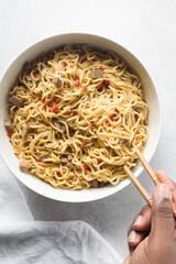 Spicy noodles with chopped chilli in a large bowl, Noodles with diced peppers in a white bowl