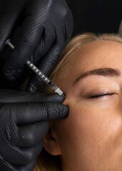 Closeup of Caucasian woman gets botox cosmetic injection in eye area. Beauty physician inserts...