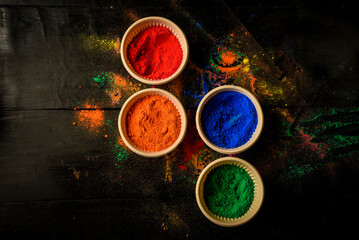 top view of colorful traditional holi powder in bowls isolated on dark background.Space for text . happy holi.Concept Indian color festival called Holi