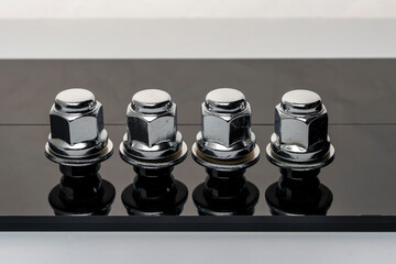 Shiny new wheel nuts on a dark background with reflection
