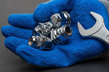 Shiny new wheel nuts and a wrench in the hand of a car mechanic