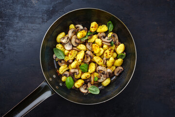 Traditional Italian gnocchi di patate with mushrooms as top view in a frying pan with copy space