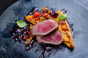 Traditional roasted Italian panettone tagliata di manzo with sliced beef steak and vegetable served as close-up on a Nordic design plate