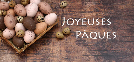 Carte de Pâques : Nid de Pâques avec œufs de Pâques et œufs de caille dans des tons naturels de marron et de beige. Avec le texte Joyeuses Pâques.