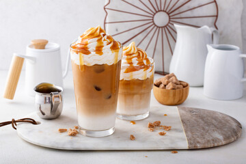 Iced caramel latte in a tall glass with drips of caramel sauce - obrazy, fototapety, plakaty