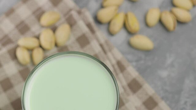 Pistachio milk in a glass on a gray concrete background. Organic lactose free pistachio milk and pistachios. Top view camera
