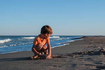 child playing with sand running jumping on the ocean