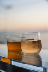 Glass of rose wine on glass table with blurred sunset in background on summers evening