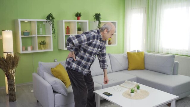 Old man suffering from herniated disc is in pain, he is disturbed.
Elderly man with hernia patient walking and moving holding his waist at home.
