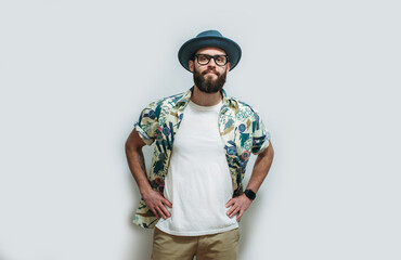 Young bearded hipster wearing Hawaiian shirt, hat and white blank t-shirt with copy space for text or logo. Layout for design