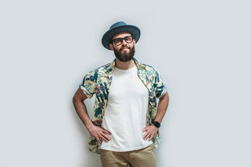 Young bearded hipster wearing Hawaiian shirt, hat and white blank t-shirt with copy space for text or logo. Layout for design