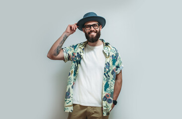 Young bearded hipster wearing Hawaiian shirt, hat and white blank t-shirt with copy space for text or logo. Layout for design