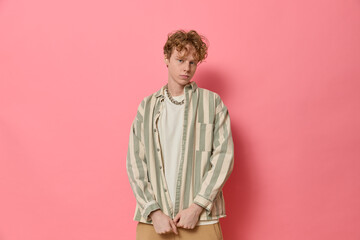 Studio fashion portrait of young confident curly haired ginger man with freckles in trendy clothes...