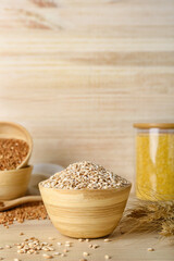Bowl with pearl barley on wooden background