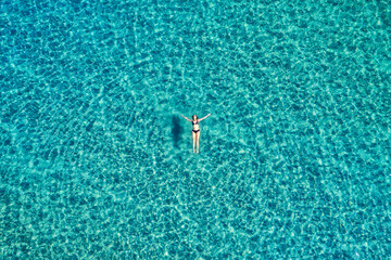 Aerial view of a woman floating on crystal clear turquoise sea water