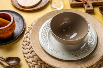 Beautiful table setting with plates and bowl on yellow background
