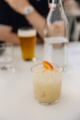 Peachy coloured mocktail/cocktail on table, sitting across from date with beer