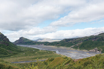 Fototapeta na wymiar Green mountains with curvy river on a cloudy day while hiking trail in Iceland