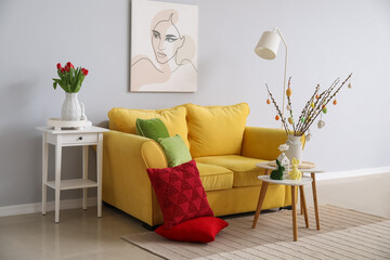 Interior of living room with Easter decor, yellow sofa and tables