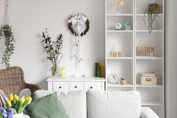 Interior of light living room with Easter wreath on white wall