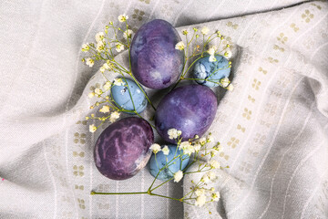 Painted Easter eggs and gypsophila flowers on white tablecloth