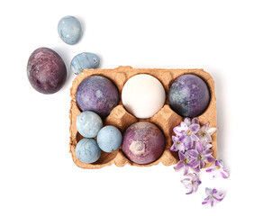 Obraz na płótnie Canvas Package with painted Easter eggs and violet flowers isolated on white background