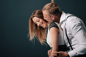 Fototapeta premium young sensual couple is lost in their own world of love and desire. Their bodies entwined as they share an intimate moment when he kiss her neck and she smiles