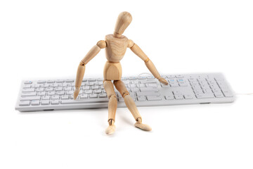 A wooden artist's mannequin sitting on a computer keyboard, suggesting or parodying artificial...