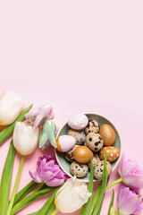 Composition with plate of Easter quail eggs, bunnies and tulip flowers on pink background