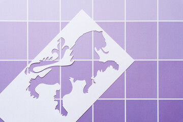 paper stencil with heraldic figure cutout on checkered purple sheet with lines