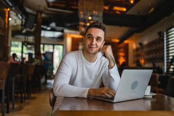 Obraz premium One man young adult caucasian male working on laptop computer at cafe