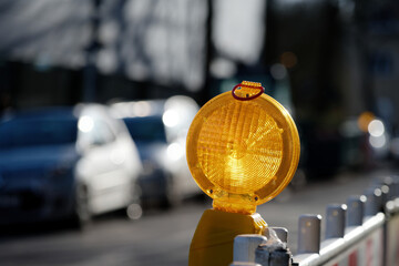 lighted construction site light on a barrier grid of a road construction site in front of blurred...