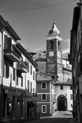 Street with a gate and a stone bell tower with a clock in the town of Gradoli