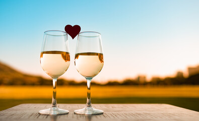 two glasses of wine and hear on sunset nature background 