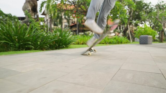 Man skateboarder skateboarding and jumping 360 flip trick on local skatepark in sunny summer. Skateboarder riding skateboard jumping flip trick.