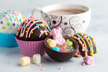 Easter hot chocolate bombs with a cup of cocoa in behind.