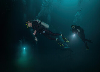 three divers using their flashlights in a cenote in mexico