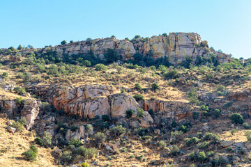 Fototapeta na wymiar Sheer cliff faces in the hills and ridges of great outdoors in wild western arizona late in afternoon shade and sun