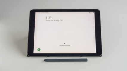 White lock screen tablet and stylus pen on desk.