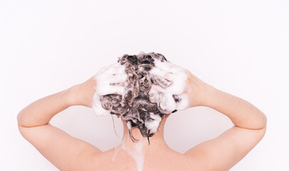Lady washing her hair with shampoo against white background.
