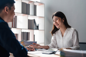 Two business people talk project strategy at office meeting room. Businessman discuss project planning with colleague at modern workplace while having conversation and advice on financial data report.