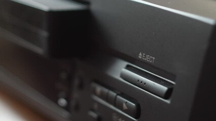close-up finger presses the eject button and the video cassette is taken out of the video player. selective focus. video recording on a vintage video cassette.