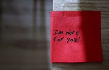 Red sticky note with text written I'M HERE FOR YOU   - concept of a cheer up note to someone to...